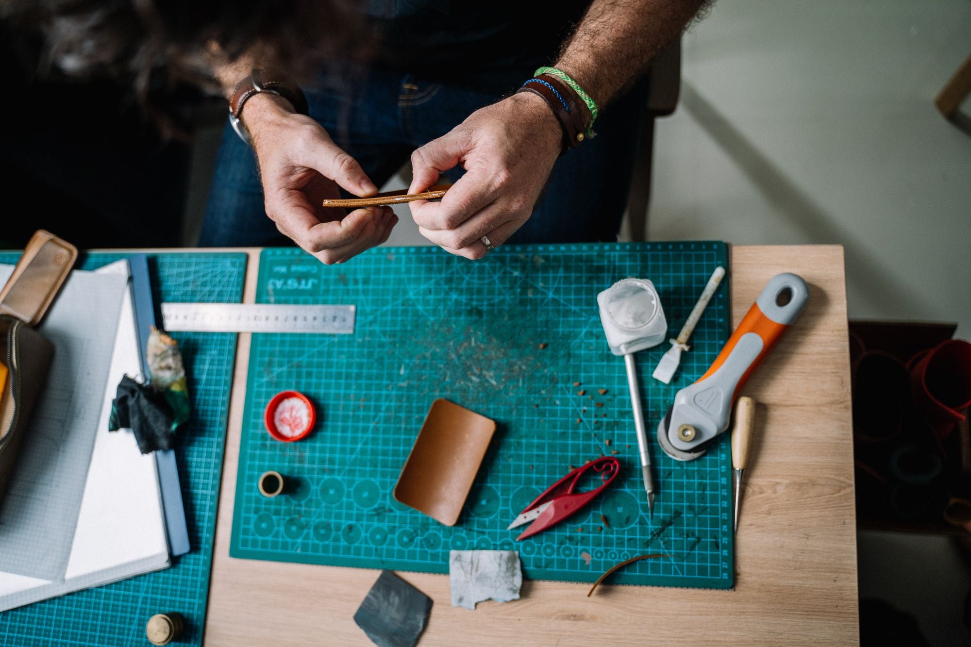 Hands crafting leather on a workbench