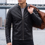 Men's black faux leather biker jacket with quilted shoulders, three-quarter lifestyle view with shoulder bag