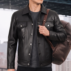 Men's black button-front faux leather trucker jacket, lifestyle view with shoulder bag