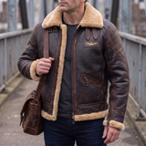 Men's brown faux leather aviator jacket with plush trim, lifestyle view with shoulder bag