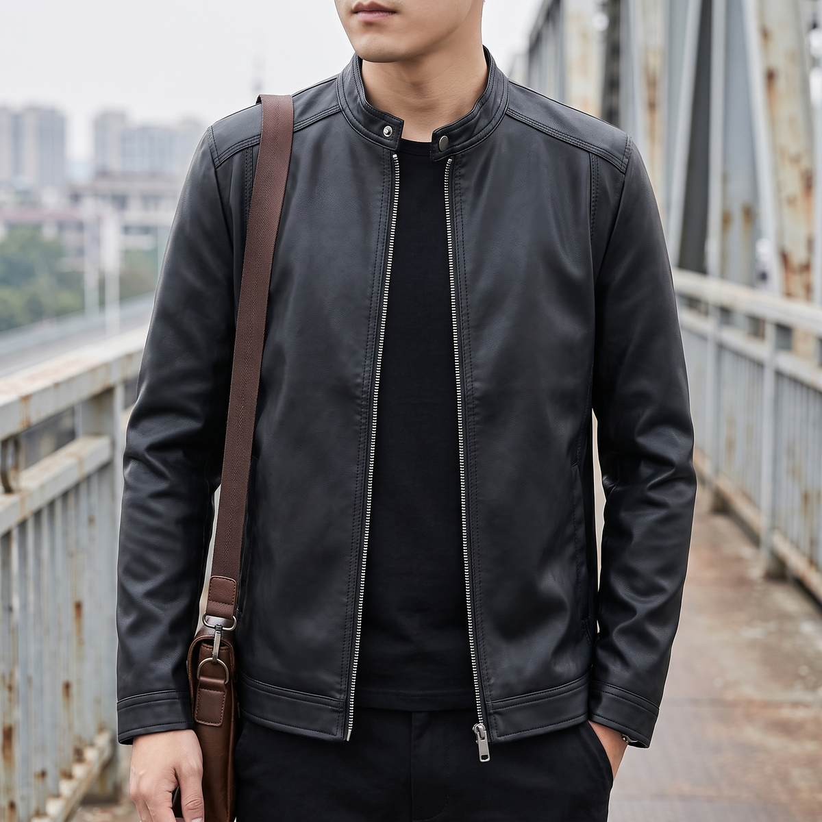 Men's black minimalist faux leather racer jacket, lifestyle view with shoulder bag