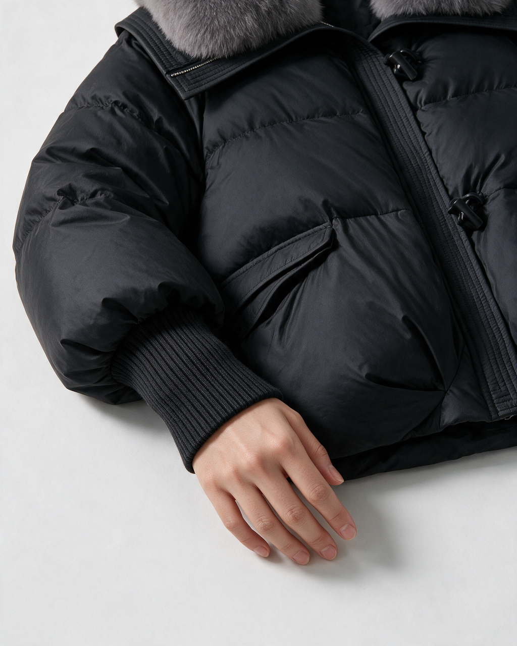 Black jacket ribbed cuff and flap-pocket detail.
