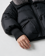 Black jacket ribbed cuff and flap-pocket detail.