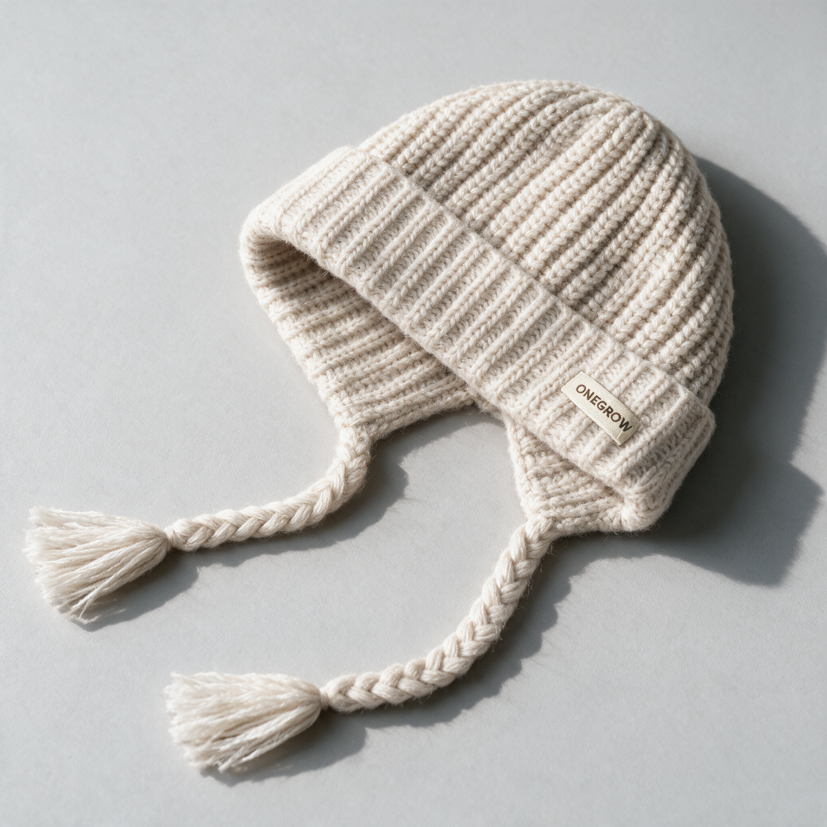 Off-white knit earflap hat with braided ties